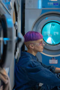 紫发青年倚靠自助洗衣店机器旁