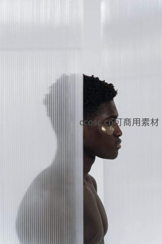 黑人青年贴眼膜，半隐于磨砂玻璃后