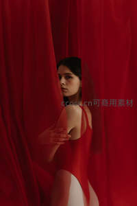 红幕之后女子回眸，红色紧身衣显曲线