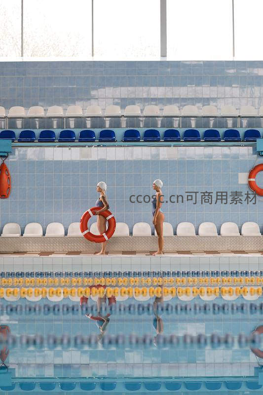 泳池畔两位女救生员持圈伫立