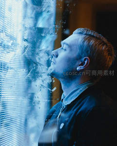 蓝调光影中男子凝望窗棂