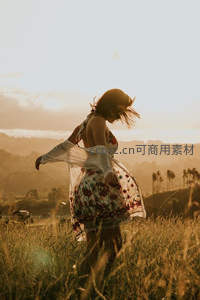 夕阳下女子旋转于金色草丛，裙摆飞扬