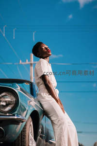 白衣女子倚靠复古跑车仰望蓝天