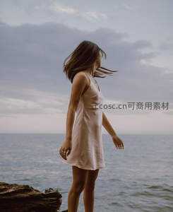 海边岩石上迎风伫立的女子