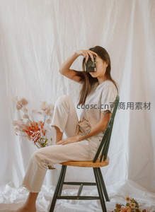 女子持复古相机静坐花旁