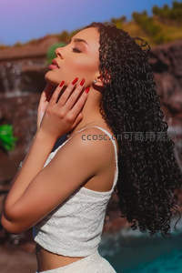 卷发女子闭目享受自然瀑布风光