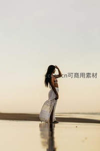 沙滩暮色中白衣女子凝望远方