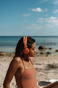沙滩少女戴橙色耳机聆听海风