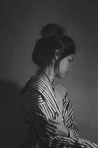 黑白光影下，条纹睡衣女子低眉沉思