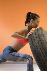 女子健身房内奋力推动巨型轮胎锻炼