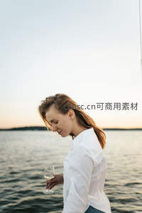 湖畔黄昏，女子手持酒杯静思