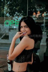 霓虹灯下，俏皮女子手握啤酒