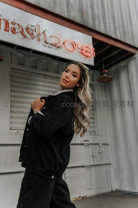 霓虹招牌下的时尚街拍，卷发女郎自信回眸