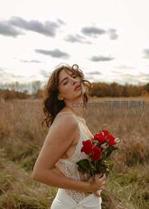 田野中手持红玫瑰的优雅女子