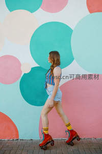 彩色波点墙前滑旱冰的时尚女孩