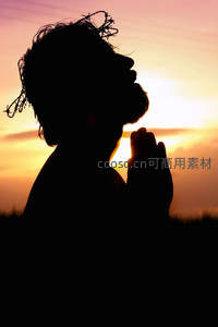 夕阳下双手合十祈祷的剪影