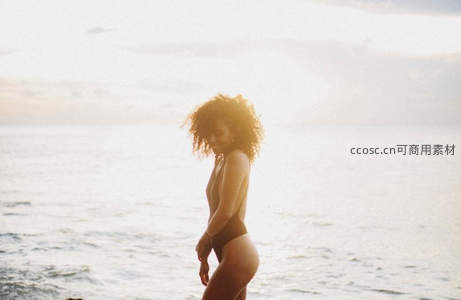 夕阳海面上漫步的卷发女子背影