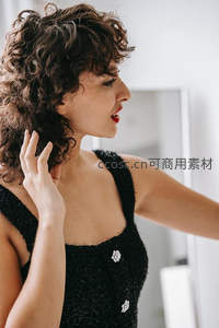 卷发女子轻抚秀发展现迷人姿态