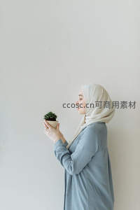 戴头巾女子静立墙边，手捧多肉植物凝神欣赏