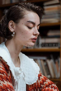 书架前女子沉思，复古毛衣显文艺气质