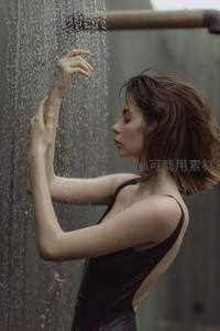 雨中女子轻触水帘，黑衣湿发尽显优雅