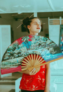 红衣女子手持彩绘折扇闭目养神