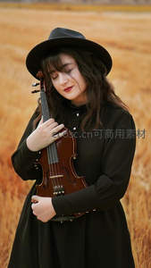 田野里戴帽女子怀抱小提琴