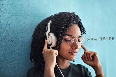 戴耳机的卷发女子闭眼享受音乐