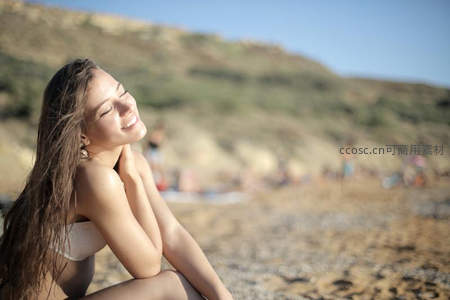 海滩上女子微笑享受阳光与海风