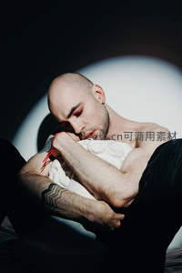 聚光灯下的沉睡男子，纹身与柔光交织