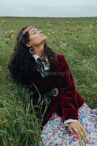 红丝绒外套女子闭目享受草原微风