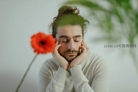 男子手托脸颊静思旁有橙色花朵