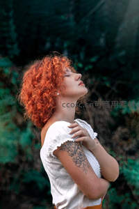 红发女子仰望天空森林中享受阳光