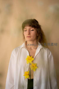 白衣女子闭目静思，黄花点缀胸前