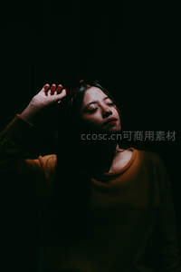 暗影中女子仰首，手抚发丝若有所思