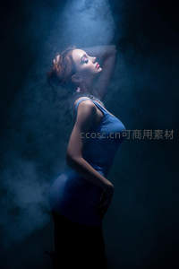 烟雾缭绕蓝衣女，侧影优雅显曲线
