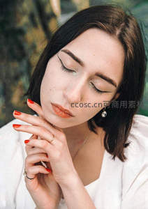 闭目沉思的女子，红甲轻抚脸颊