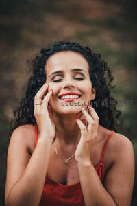 卷发女子微笑抚摸脸颊的幸福时刻
