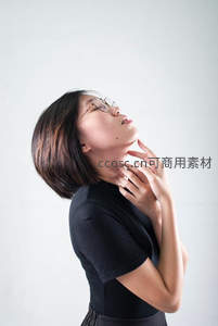女子仰首轻抚颈部，简约背景显优雅