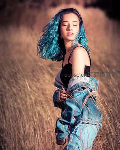 蓝发少女置身金黄草丛随风舞动