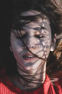 光影斑驳下女子闭目享受风拂面庞