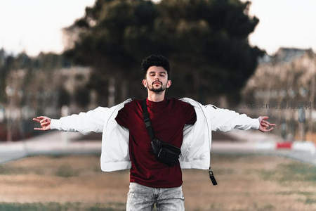 街头青年张开双臂拥抱自由，都市背景下的洒脱瞬间