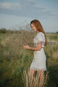 白衣少女怀抱干草束伫立田野间