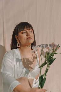 室内光影中女子手捧鲜花闭目冥想