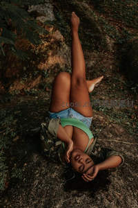 黑肤女子倒卧岩石上享受森林清凉