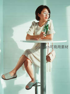 浅色碎花裙女子手握啤酒倚靠吧台休憩