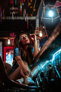 霓虹灯下女子坐于复古机械旁凝视远方