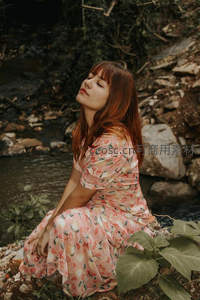 红发女子溪边静坐，享受自然宁静