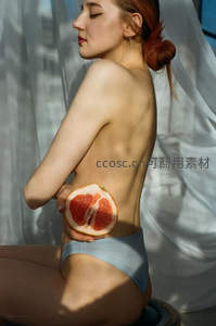 女子背影持柚子，光影交织显柔美