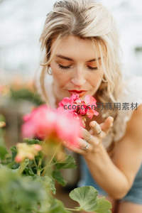 金发女子轻嗅粉花享受芬芳